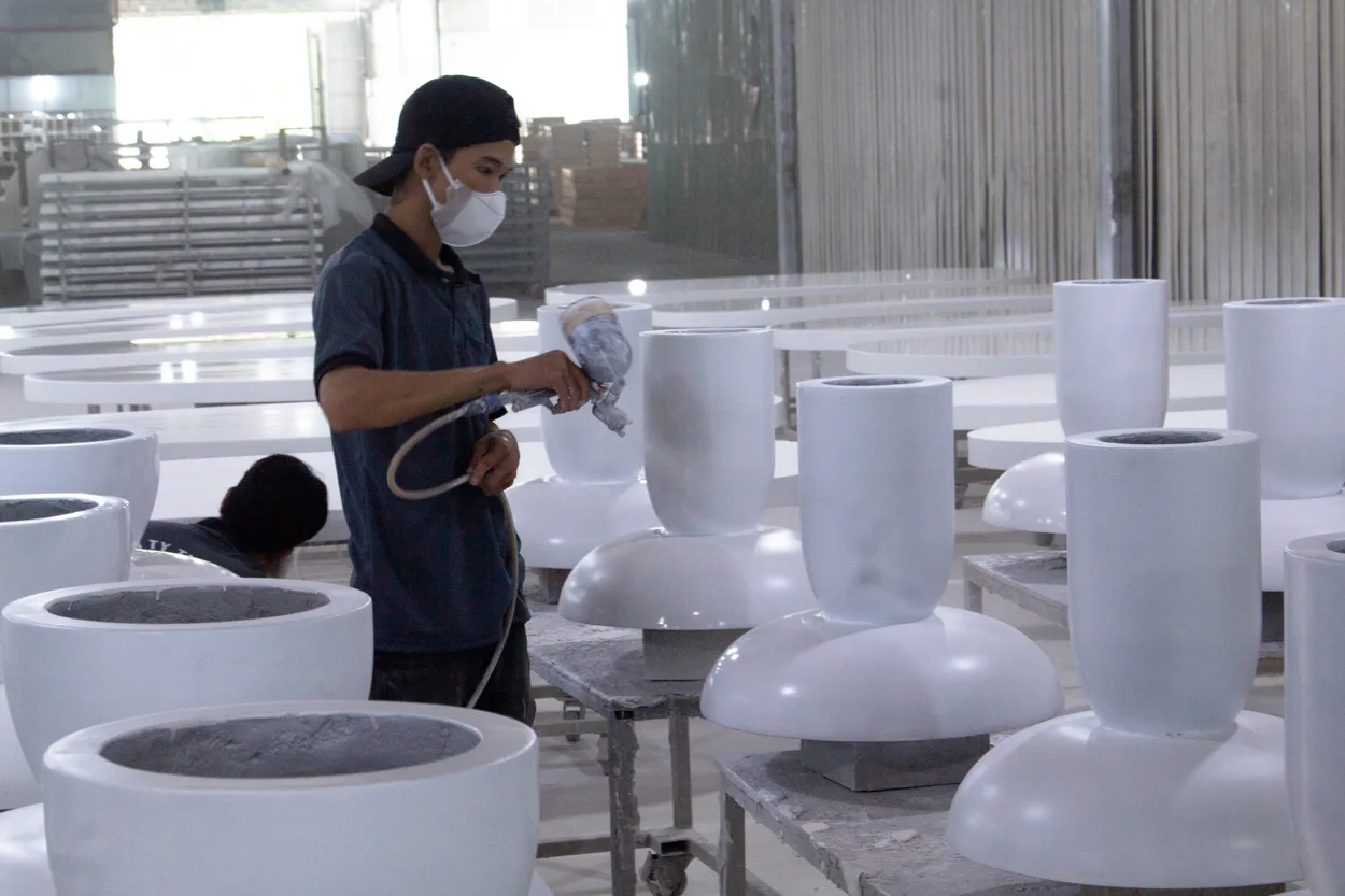 Vietnam worker spraying finish on GFRC furniture products, showing how material and finishing processes impact the Vietnam furniture cost breakdown.