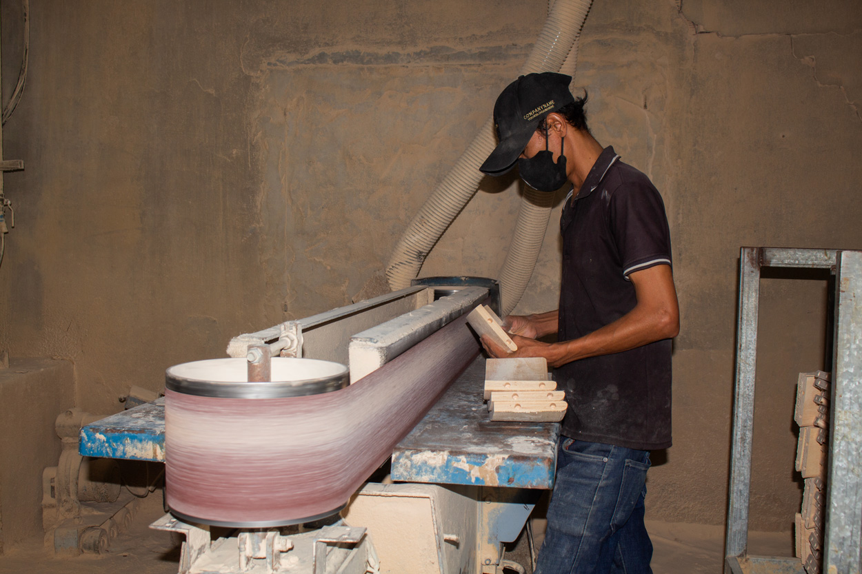 Vietnam furniture factory worker at Aurora Craft finishing wooden parts with machinery, illustrating labor cost advantage in vietnam vs china furniture cost comparison