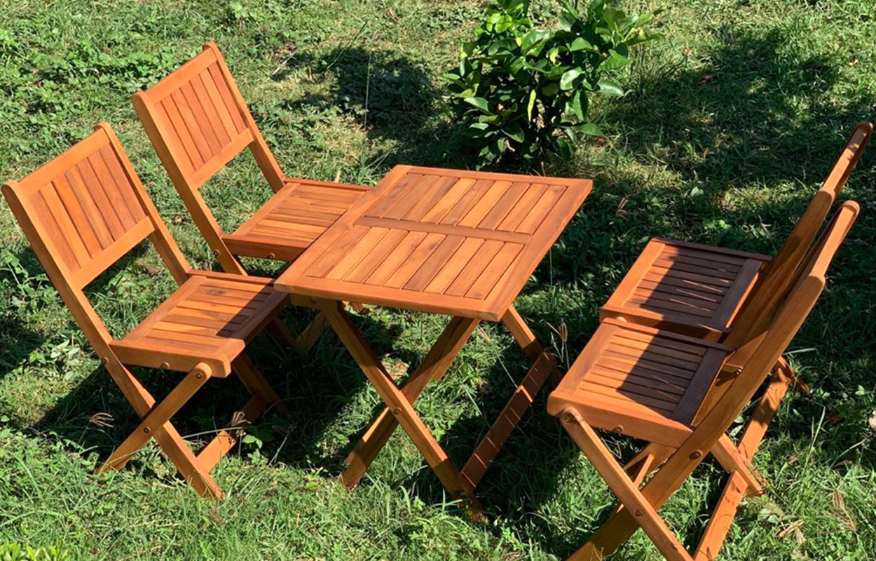 Acacia wood outdoor folding table and chair set placed in a garden, showing durable and moisture-resistant wood for outdoor furniture.