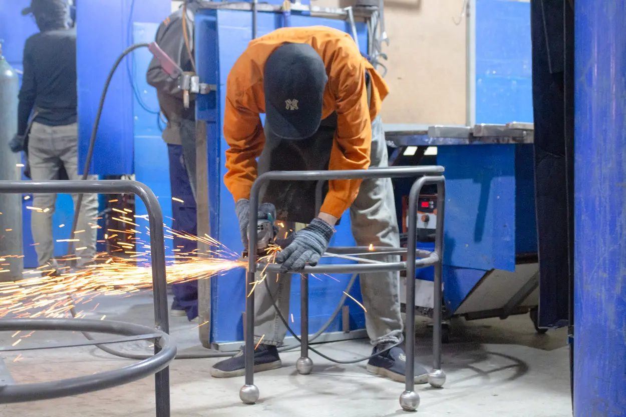 Worker fabricating metal furniture at Aurora Craft’s factory, producing durable furniture for retailers.