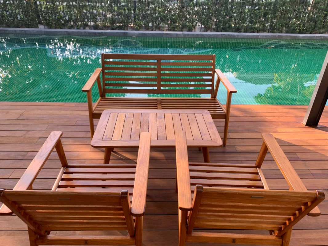 Teak wood outdoor furniture set on a patio beside a swimming pool, showcasing durable wood for outdoor furniture.