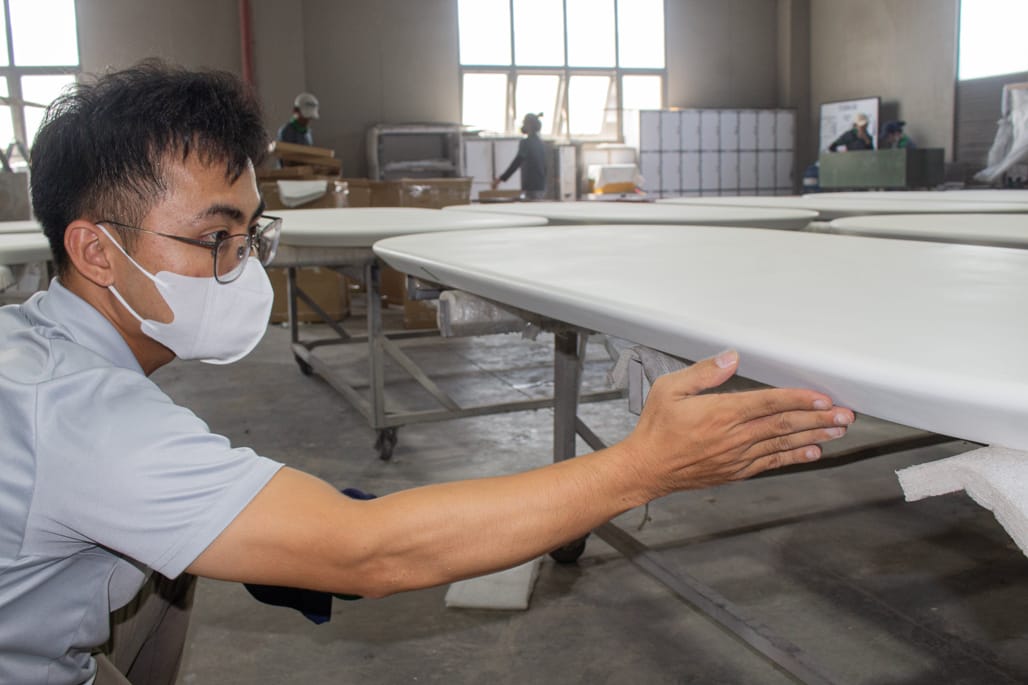 Aurora Craft QC inspector checking a finished furniture surface during final quality control