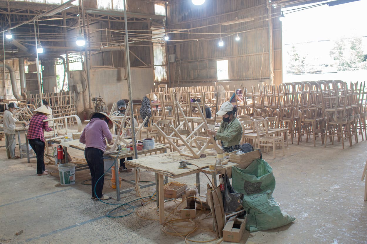 Workers assembling wooden furniture at Auroracraft's factory, illustrating coordinated production planning to optimize lead time and reduce furniture manufacturing cost.