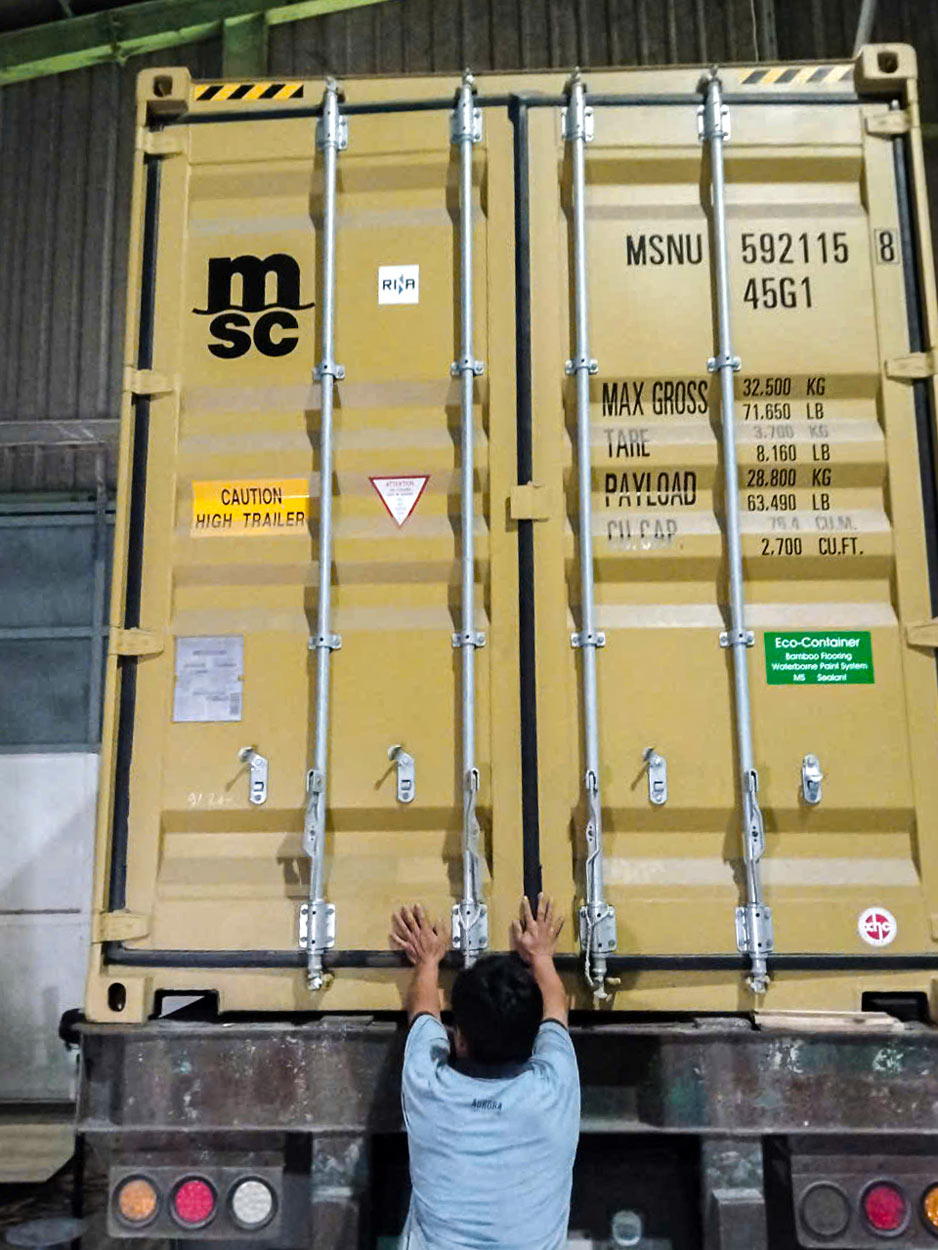 Worker handling the closed doors of a shipping container on a truck before inland transportation