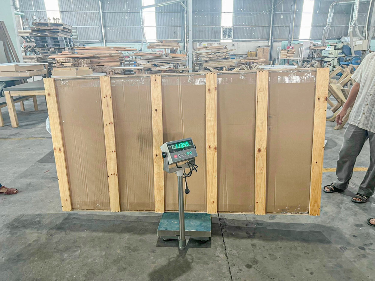Large reinforced furniture shipping package positioned on a digital scale for gross weight measurement