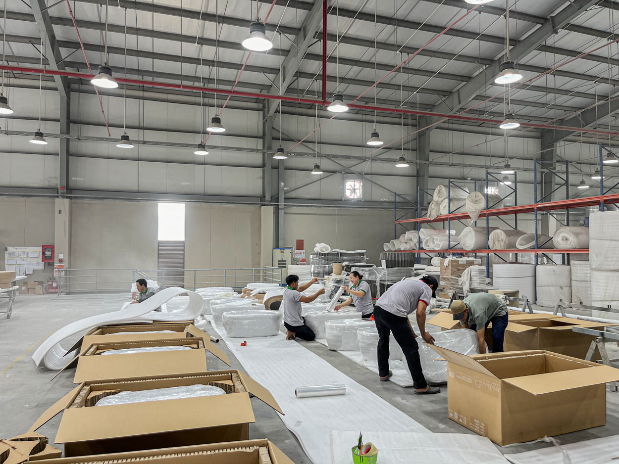 Workers preparing protective packaging for furniture with cushioning materials and export cartons
